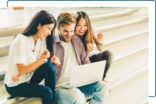 three students smiling looking at a laptop