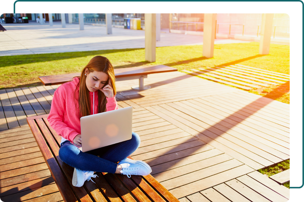 student working on laptop outside on bench